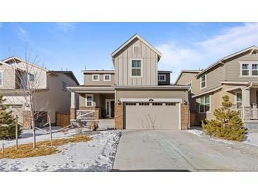 Two-story house with gray siding, two-car garage, and snowy front yard at 697 N Bersshine Ct, Watkins, CO 80137