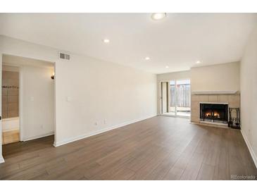 Bright living room with wood floors, fireplace and a sliding glass door to the outside at 865 S Quebec St # 103B, Denver, CO 80247