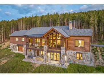 Stunning two-story home with a stone foundation and a backdrop of towering pine trees at 242 Point View Pl, Breckenridge, CO 80424