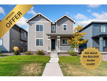 Charming two-story home with gray siding, front porch, and manicured lawn at 18060 E 106Th Pl, Commerce City, CO 80022