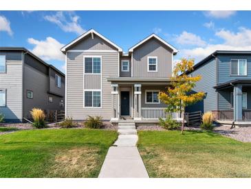 Charming two-story home with landscaped yard and inviting covered front porch at 18060 E 106Th Pl, Commerce City, CO 80022