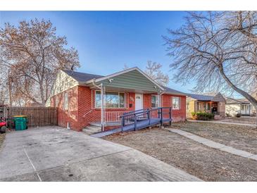 Charming single-story brick home with a ramp and front yard featuring mature trees and a cozy front porch at 1051 Lima St, Aurora, CO 80010