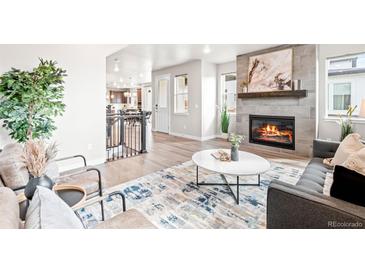 Inviting living room with a cozy fireplace, stylish rug, and comfortable seating arrangement at 9700 E 63Rd Pl, Denver, CO 80238