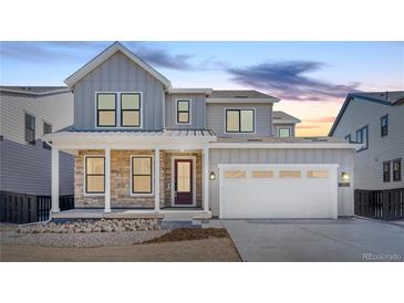 Beautiful two-story home with stone accents, covered porch, white garage door and a well-manicured lawn at 8864 Moonshimmer Trl, Littleton, CO 80125