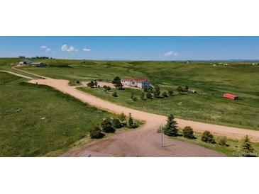 Expansive property featuring a charming home with beautiful landscaping and vast green fields on a sunny day at 29333 Rawhide Ct, Elizabeth, CO 80107
