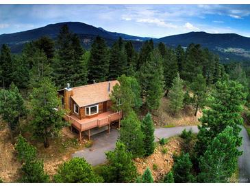 Charming mountain home surrounded by lush trees with a large wrap around deck and stunning mountain views at 10042 Buena Vista Dr, Conifer, CO 80433