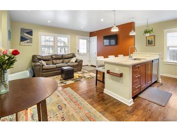 Inviting living room and kitchen area featuring hardwood floors, a kitchen island, and a comfortable seating area at 2665 S Pennsylvania St, Denver, CO 80210