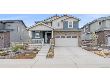 Charming two-story home featuring stone accents, gray siding, a two-car garage, and manicured landscaping at 8268 Mt Harvard Rd, Littleton, CO 80125