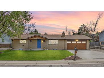 Charming ranch-style home featuring a brick exterior, blue door, manicured lawn and an attached garage at 11896 W 107Th Ave, Westminster, CO 80021