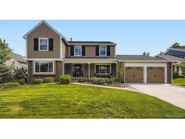 Charming two-story home featuring a well-manicured front lawn, brick accents, and a two-car garage at 5988 E Jamison Ln, Centennial, CO 80112