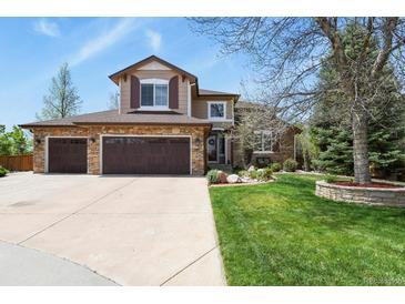 Beautiful two-story home featuring a three-car garage, stone accents, lush lawn, and mature trees at 9536 W Avalon Dr, Littleton, CO 80127