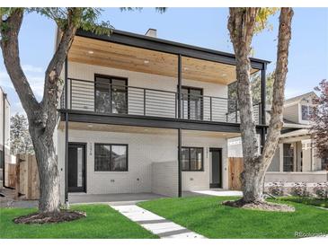 Two-story home features a white brick facade, black framed windows, wood ceiling, and a well-manicured lawn at 1374 Perry St, Denver, CO 80204