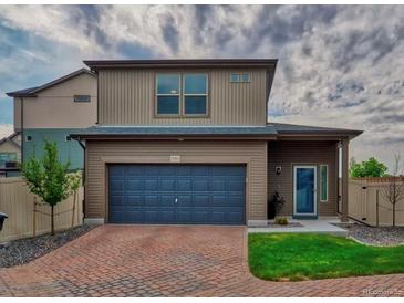 Charming two-story home featuring a brick driveway, a two-car garage, and a well-maintained lawn at 17910 E 54Th Ave, Denver, CO 80249