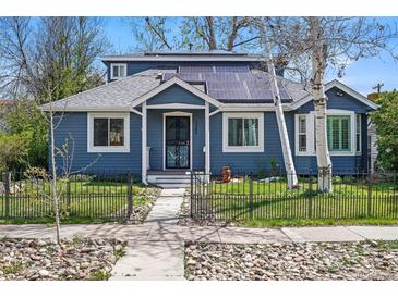 Charming blue home with solar panels, walkway, metal fence and lush trees at 2244 Fenton St, Edgewater, CO 80214