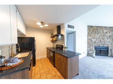 Charming kitchen features modern appliances, dark countertops and unique backsplash at 3100 S Federal Blvd # 307, Denver, CO 80236