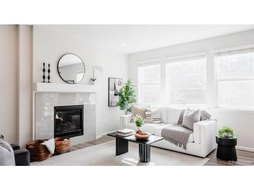 Bright living room featuring a fireplace, large windows, and modern decor for a comfortable and inviting space at 17850 W 94Th Dr, Arvada, CO 80007