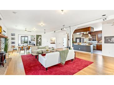 Bright open-plan living room featuring hardwood floors, white sofas and a view into the kitchen at 4730 W Moncrieff Pl, Denver, CO 80212