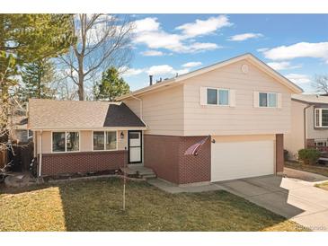 Charming home with a well-maintained lawn, brick accents, and an attached two-car garage at 6616 Zinnia St, Arvada, CO 80004