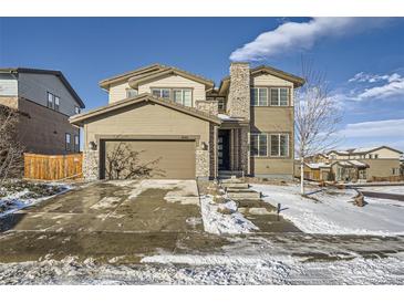 Two-story house with stone and siding accents, a three-car garage, and a landscaped yard at 14461 Mosaic Ave, Parker, CO 80134