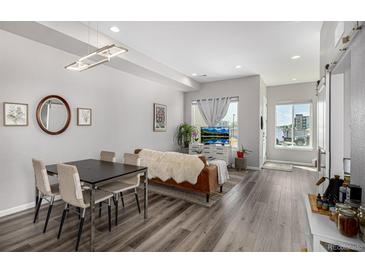 Bright living room featuring dining area, modern lighting, and stylish decor with hardwood floors at 5371 E 63Rd Pl, Commerce City, CO 80022