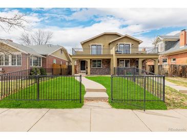 Inviting two-story home with a manicured front yard, wrought iron fence, and second story balconies at 1653 S Logan St, Denver, CO 80210