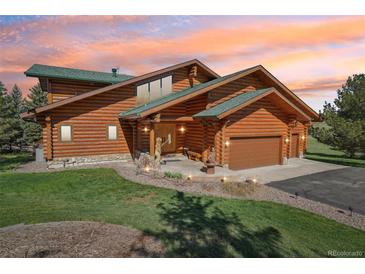 Stunning log home featuring a green roof, stone accents, and a meticulously landscaped front yard at 3557 Palmer Ridge Dr, Parker, CO 80134