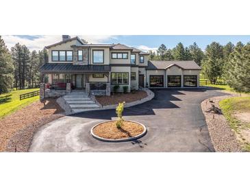 Stunning two-story home featuring stone accents, a covered front porch, and an expansive driveway with a circular turnaround at 230 S Big Meadow Trl, Franktown, CO 80116