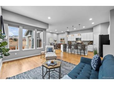 Open-concept living room featuring hardwood floors, large windows, and modern decor at 14284 W 88Th Dr # B, Arvada, CO 80005