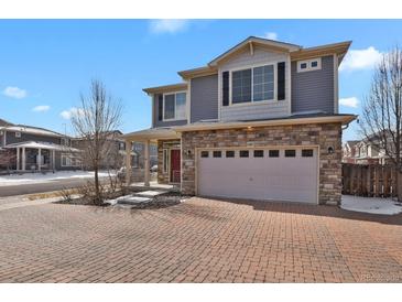 Beautiful two-story home showcasing stone accents, a spacious garage, and a well-manicured brick driveway at 26167 E Byers Pl, Aurora, CO 80018