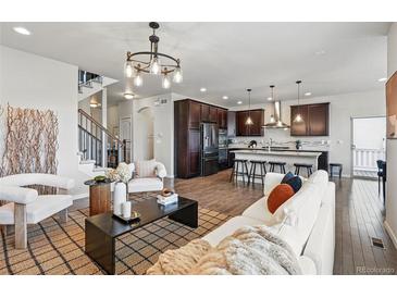 Open concept living room with hardwood floors, modern lighting fixtures, and a seamless flow into the kitchen at 2562 S Kendrick St, Denver, CO 80228
