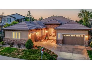 Charming single-story home featuring stone accents, a tile roof, and a well-manicured lawn at 2571 Hunters Pl, Highlands Ranch, CO 80129