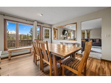 Bright dining room features wood table, mountain views, and access to the home's deck at 24 Ski Pole Ct, Breckenridge, CO 80424