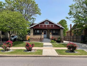 Charming brick home featuring a cozy front porch and a well-manicured lawn with vibrant rose bushes at 1418 Perry St, Denver, CO 80204