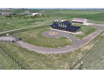 Expansive aerial view of home with circular driveway, dark metal roof, fenced perimeter, and green surrounding landscape at 3308 County Road 19, Fort Lupton, CO 80621
