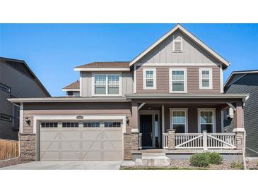 Two-story house with gray siding, a large garage, and a front porch at 10983 Memphis St, Commerce City, CO 80022