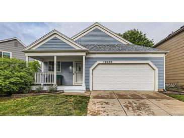 Charming exterior featuring blue siding, a front porch, an attached garage, and well-maintained landscaping at 12060 N Holly Way, Brighton, CO 80602