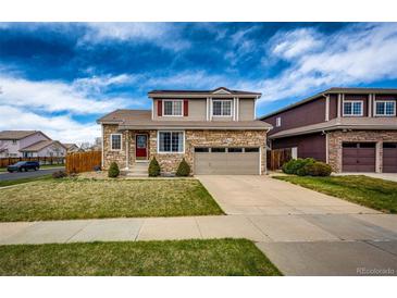 Two-story home featuring stone accents, a two-car garage, a red door, and a well-maintained front lawn at 20305 E 41St Ave, Denver, CO 80249