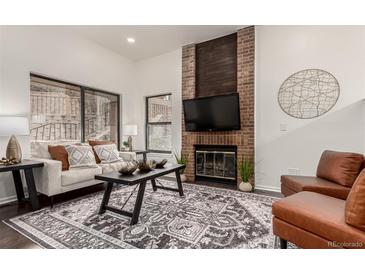 Inviting living room featuring a brick fireplace, large windows, and stylish decor at 9400 E Iliff Ave # 103, Denver, CO 80231