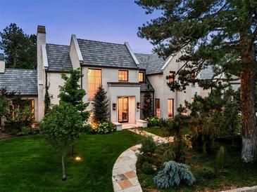 Stunning two-story white brick home featuring a tiled roof and lush, professionally landscaped front yard at 27 Polo Club Cir, Denver, CO 80209