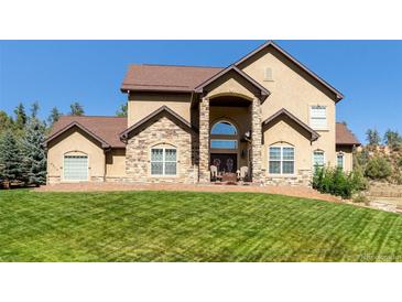 Two-story house with stone accents and a manicured lawn at 4619 Mohawk Dr, Larkspur, CO 80118