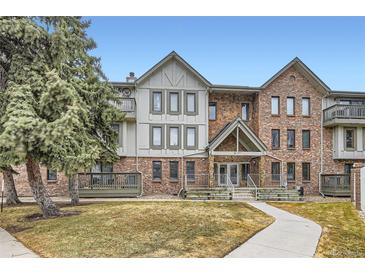 Beautiful condo exterior featuring a well-kept lawn, mature trees, and a welcoming stone-accented entrance at 6475 S Dayton St # 102, Englewood, CO 80111