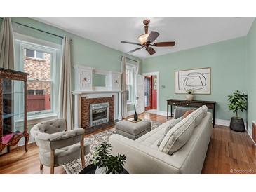 Charming living room with fireplace, hardwood floors, and natural light from large windows at 1563 N Lafayette St, Denver, CO 80218