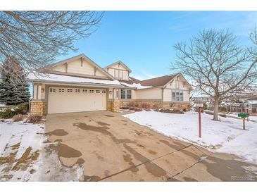 Two-story house with beige siding, stone accents, and a three-car garage at 23405 E Elmhurst Pl, Aurora, CO 80016