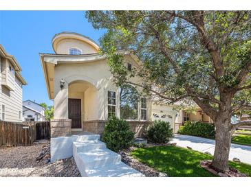 Charming stucco home with arched entry, large windows, mature trees, and well-manicured lawn in a desirable neighborhood at 9735 E 112Th Pl, Commerce City, CO 80640
