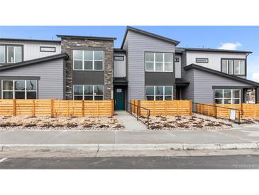 Modern townhouse featuring gray siding, stone accents, large windows, and inviting landscaping at 9468 W 58Th Ln # C, Arvada, CO 80002