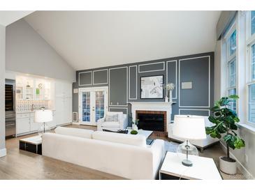 Bright living room with vaulted ceilings, fireplace, and a large window providing ample natural light at 7743 S Jersey Way, Centennial, CO 80112