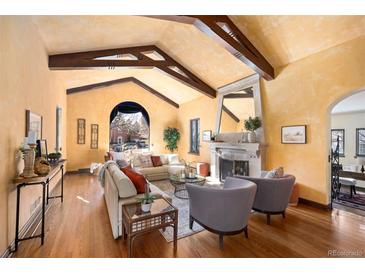 Spacious living room with vaulted ceilings, wood beams, fireplace, and hardwood floors at 6 Ivy Ln, Denver, CO 80220