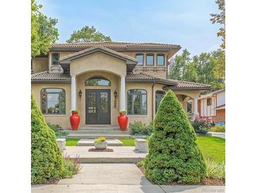 Elegant home featuring a symmetrical design, red urns, and a well-manicured lawn with trimmed bushes at 6246 W 35Th Ave, Wheat Ridge, CO 80033