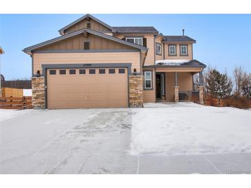 Two-story house with a beige exterior, stone accents, and a three-car garage at 17395 Leisure Lake Dr, Monument, CO 80132