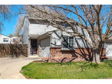 Charming two-story home featuring a well-maintained lawn, brick accents, and an attached garage, creating curb appeal at 12743 Eudora Dr, Thornton, CO 80241